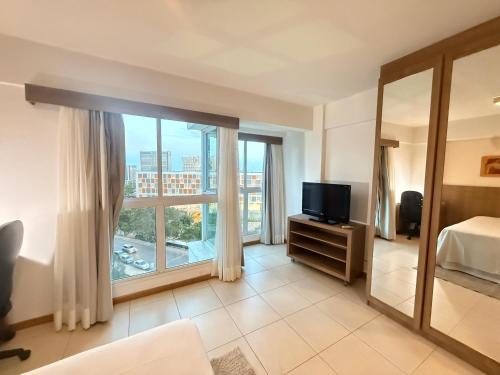 a bedroom with a bed and a tv and a window at Saint Moritz Hotel - ALM Hospedagens - Flat Particular in Brasilia