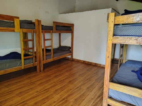 a room with three bunk beds and a wooden floor at Hostel coconut tree in Gokarna