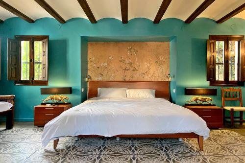 a bedroom with a large bed and blue walls at La Cortijera in Benidoleig