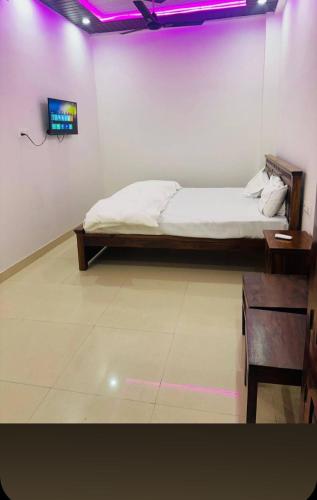 une chambre avec un lit et une télévision au mur dans l'établissement Hotel haveli, à Rāmgarh