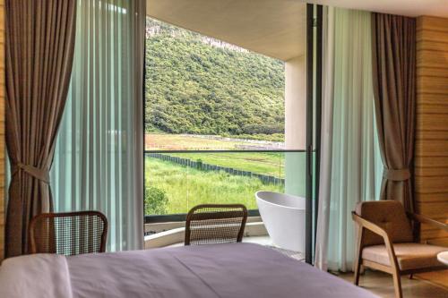 a bedroom with a large window with a tub and a bed at Viewpoint Khaoyai Hotel in Mu Si