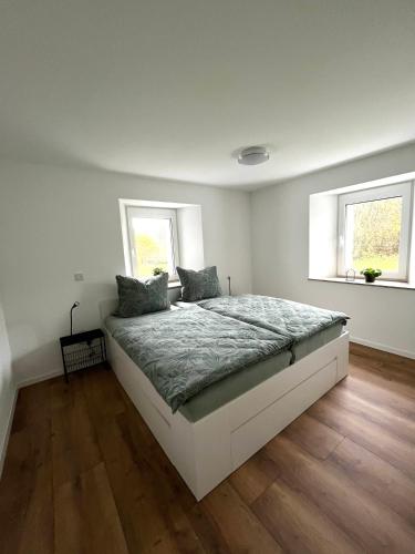 a bedroom with a large bed with two windows at Ferienwohnung Martha und Nikla in Philippsheim