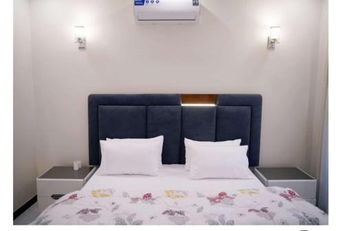 una cama con cabecera azul y almohadas blancas en Marjaan Stays Luxury Guest House in Lahore Goldberg, en Lahore