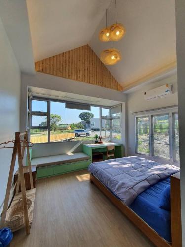 a bedroom with a bed and a desk and windows at Jacuzzi mine hills in Ban Mai