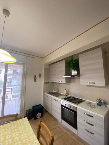 Crateri e coralli في ماسكالي: مطبخ بخزائن بيضاء وطاولة وموقد