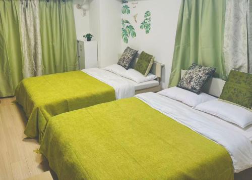 two beds in a room with green curtains at Shinjuku新宿公園 in Tokyo