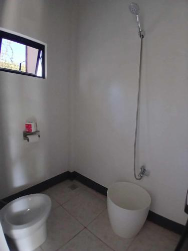 a bathroom with a toilet and a sink and a window at correashomestay in Coron