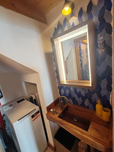 a kitchen with a sink and a mirror and a refrigerator at Chalet La montagne enchantée in San Damiano Macra