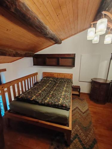 a bed in a room with a wooden ceiling at Chalet La montagne enchantée in San Damiano Macra