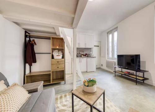 a living room with a couch and a tv at Le Petit nid cocooning - Studio chaleureux et élégant in Aubervilliers