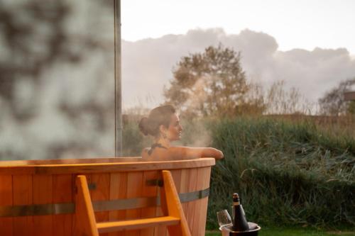 Garden Suites - Duinhotel in Burgh-Haamstede zeeland في برغ هالمستاد: فتاة صغيرة تجلس في حوض استحمام أمام النافذة