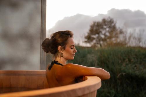 uma mulher está sentada numa banheira em Garden Suites with private hot tub em Burgh Haamstede