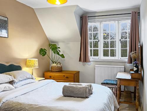 a bedroom with a bed and a desk and a window at Bossington Green Cottage in Porlock
