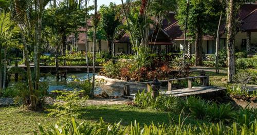 ein Garten mit Teich und Bank vor einem Haus in der Unterkunft Annika Koh Chang , Formerly Ramayana Koh Chang Resort & Spa in Ko Chang