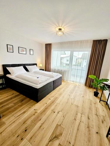 Un dormitorio con una cama grande y suelo de madera. en Basilisk Homes - in Grenzach-Wyhlen bei Basel - 4 x Moderne Fewos je 1bis2, 1bis4 oder 1bis6 Pers mit Küche und Balkon oder Terrasse - Parkplätze vorhanden, en Grenzach-Wyhlen
