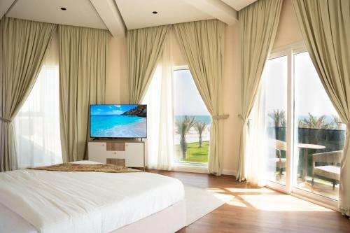 Un dormitorio con una cama grande y grandes ventanales. en Dana Beach Resort, en Al Sharqiyah