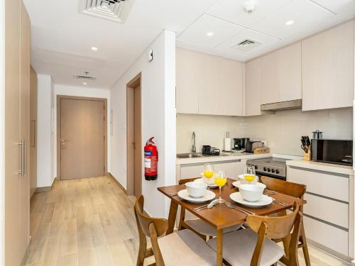 a kitchen and dining room with a wooden table and chairs at Elite Nest - Chic Studio, 1 min to Ferrari World & SeaWorld in Abu Dhabi
