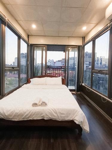 a large bed in a room with large windows at Lucky Motel - Self Checkin in Hanoi