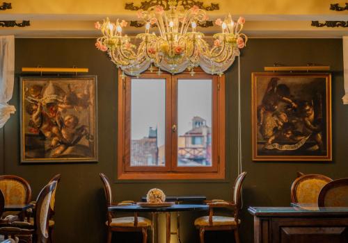Un comedor con una lámpara de araña y cuadros en las paredes. en Palazzo Bembo - Exclusive Accommodation, en Venecia