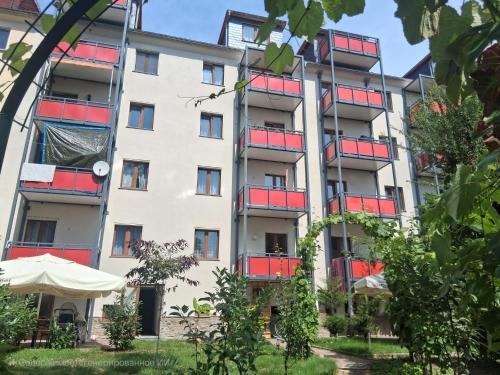 ein Wohnhaus mit roten Balkonen und einem Regenschirm in der Unterkunft Casa Delli Gatti in Leipzig