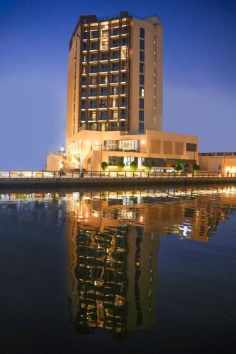 a building with its reflection in the water at night at Pavilion Hotel Al Jaddaf - Managed by Nooa in Dubai