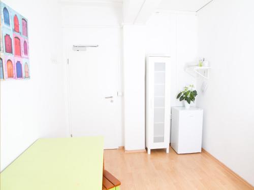 a white room with a mirror and a plant on a dresser at PM-Rooms in Munich