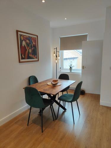 ein Esszimmer mit einem Holztisch und grünen Stühlen in der Unterkunft luxury Maisonette near beach in Morecambe