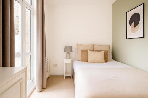 a white bedroom with a bed and a window at Superb 2 Bed Apartment in Battersea in London