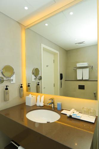 a bathroom with a sink and a large mirror at Pavilion Hotel Al Jaddaf - Managed by Nooa in Dubai