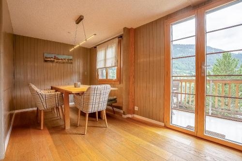 a dining room with a table and chairs and windows at Reste Fidèle Duplex in Fiesch