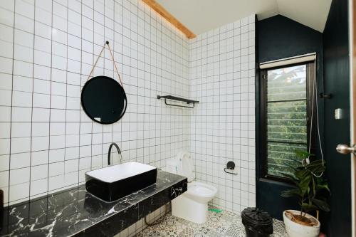a white tiled bathroom with a sink and a toilet at Cosy Pool Villa at Khaoyai in Nong Nam Daeng