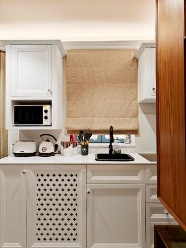 a white kitchen with a sink and a microwave at Zebbuga Lavish Suite 2 in Żebbuġ