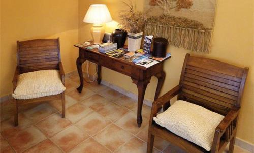a desk with a lamp and two chairs in a room at Hotel Restaurante el Fornon in Novellana