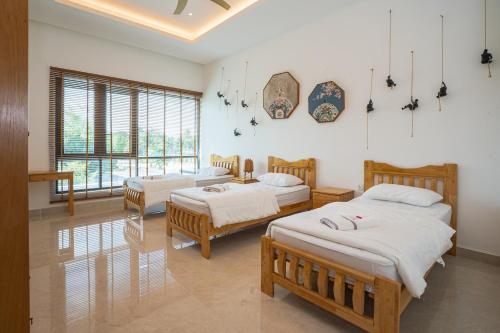 Un dormitorio con tres camas y una gran ventana. en Cheekaaboo Playhouse Ipoh, en Ipoh
