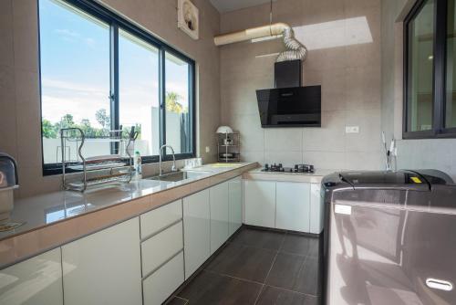 Una cocina con gabinetes blancos y una ventana grande. en Cheekaaboo Playhouse Ipoh, en Ipoh