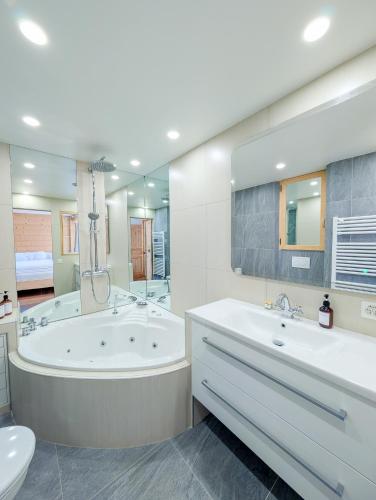 a bathroom with two sinks and a tub and a toilet at Appt de charme dans chalet - cosy & nature in Villars-sur-Ollon