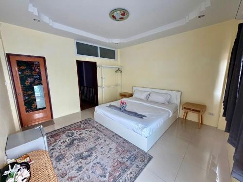 ein Schlafzimmer mit einem weißen Bett und einem Teppich in der Unterkunft TIDE & TRIBE HOSTEL Phangan in Thongsala