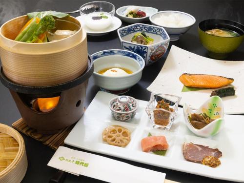 einen Tisch mit einem Teller mit Lebensmitteln und Schüsseln in der Unterkunft Saikatei Jidaiya in Kaminoyama
