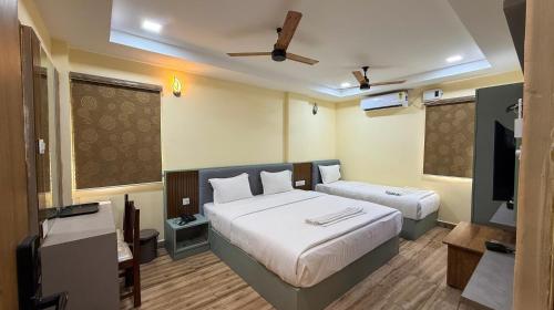 a bedroom with two beds and a flat screen tv at Lakshmi Narayana Grand in Kanchipuram