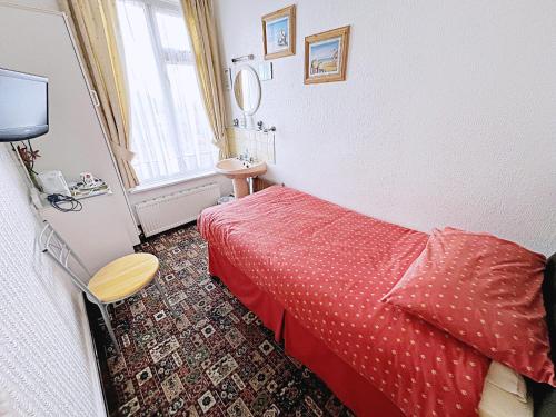 ein Hotelzimmer mit einem roten Bett und einem Waschbecken in der Unterkunft Affordable and Comfortable Guest House by Sea in Cleethorpes