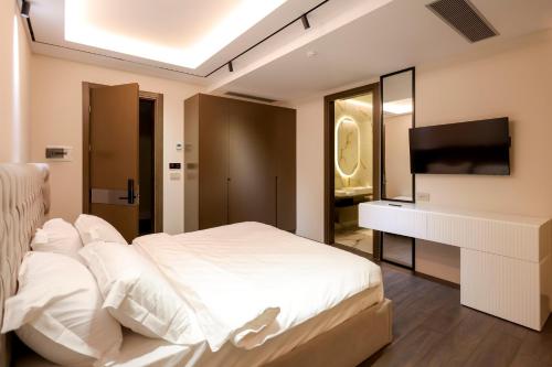 a bedroom with a white bed and a television at Si'Hana Hotel in Elbasan