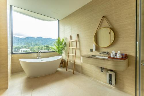 a bathroom with a tub and a sink and a mirror at Viewpoint Khaoyai Hotel in Mu Si