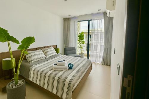 a bedroom with a bed with towels and a plant at Rose & Golf at Rose Apple Square in Siem Reap