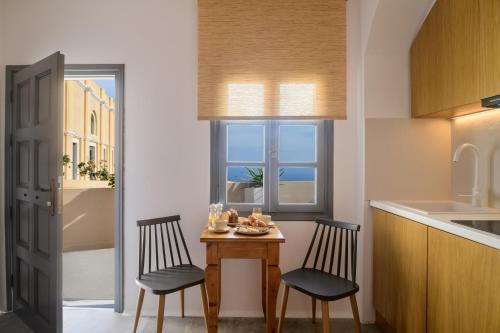 a small kitchen with two chairs and a table and a window at Themis Coddess Cave Suites in Santorini