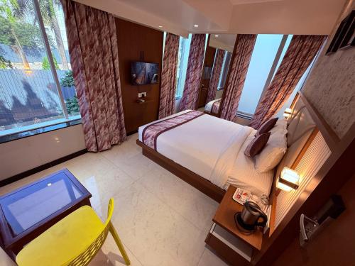 a hotel room with a bed and a desk and a television at Hotel Pearl Residency Thane in Thane