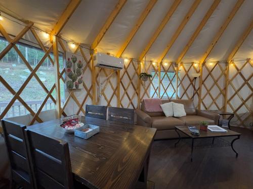 a room with a table and a couch in a yurt at Pala Chino Yurt - Next to Nantahala Weddings in Aquone