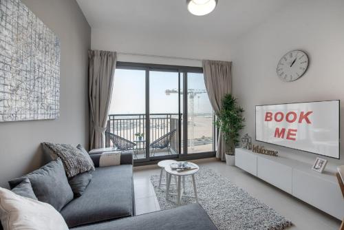 a living room with a couch and a clock at Free housekeeping visits during your stay - StayShort - Extravagant 1BR near Town Square - Sleeps 4 in Nadd Shubayḩ