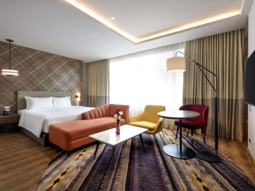 a hotel room with a bed and a couch at Mercure Bangkok Sukhumvit 24 in Bangkok