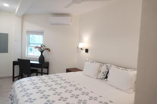 ein weißes Schlafzimmer mit einem Bett und einem Schreibtisch in der Unterkunft Karana Suite One Bedroom - K3 in Long Bay Hills