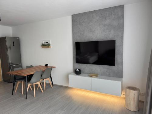 a dining room with a table and a television on a wall at Jedeme Lipno in Kobylnice